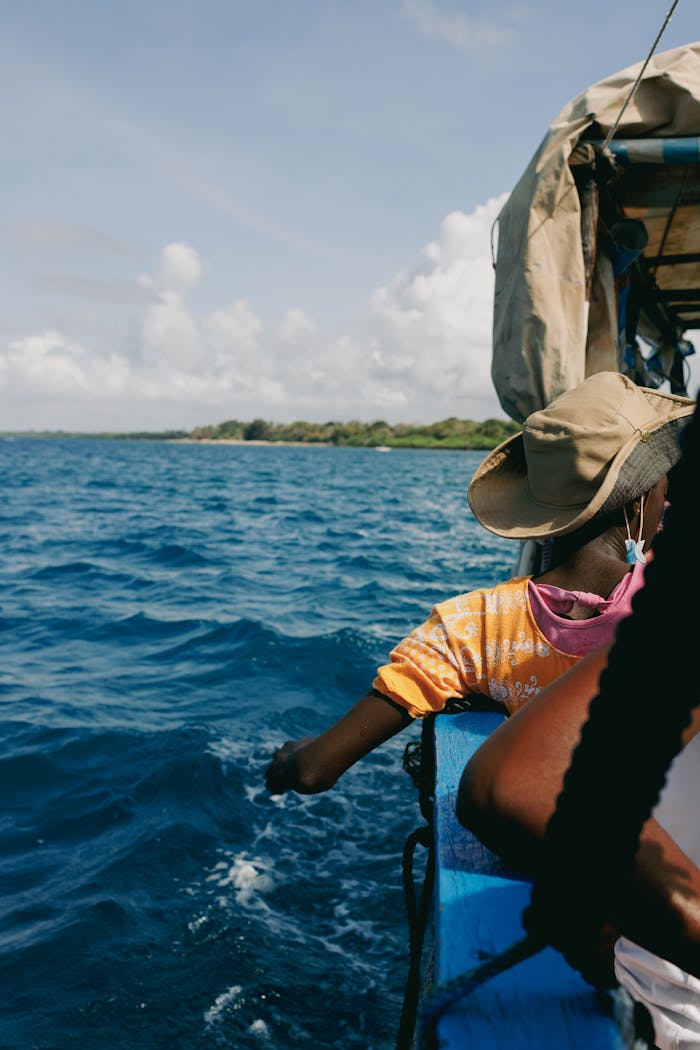 A serene boating experience along the Kenyan coast under a sunny sky with lush land in the distance.