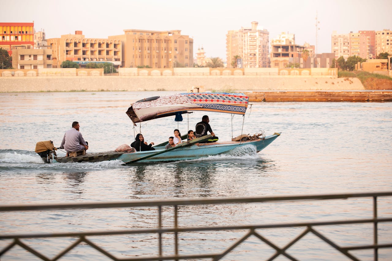 our-services-2 Group enjoying a traditional boat ride on a river with city buildings in the background.