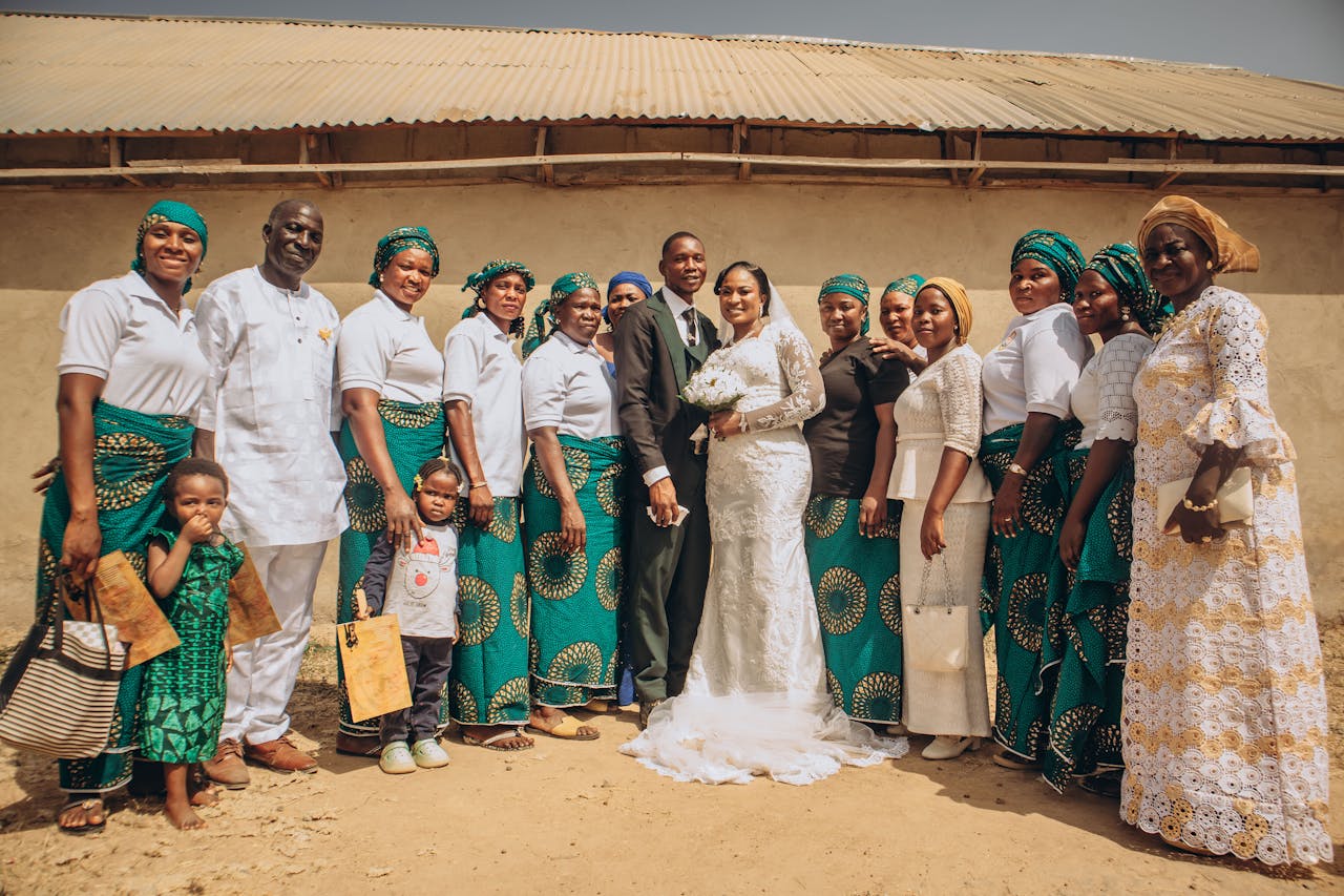 services-03 A joyful group photograph at a multicultural wedding ceremony outdoors in daylight.